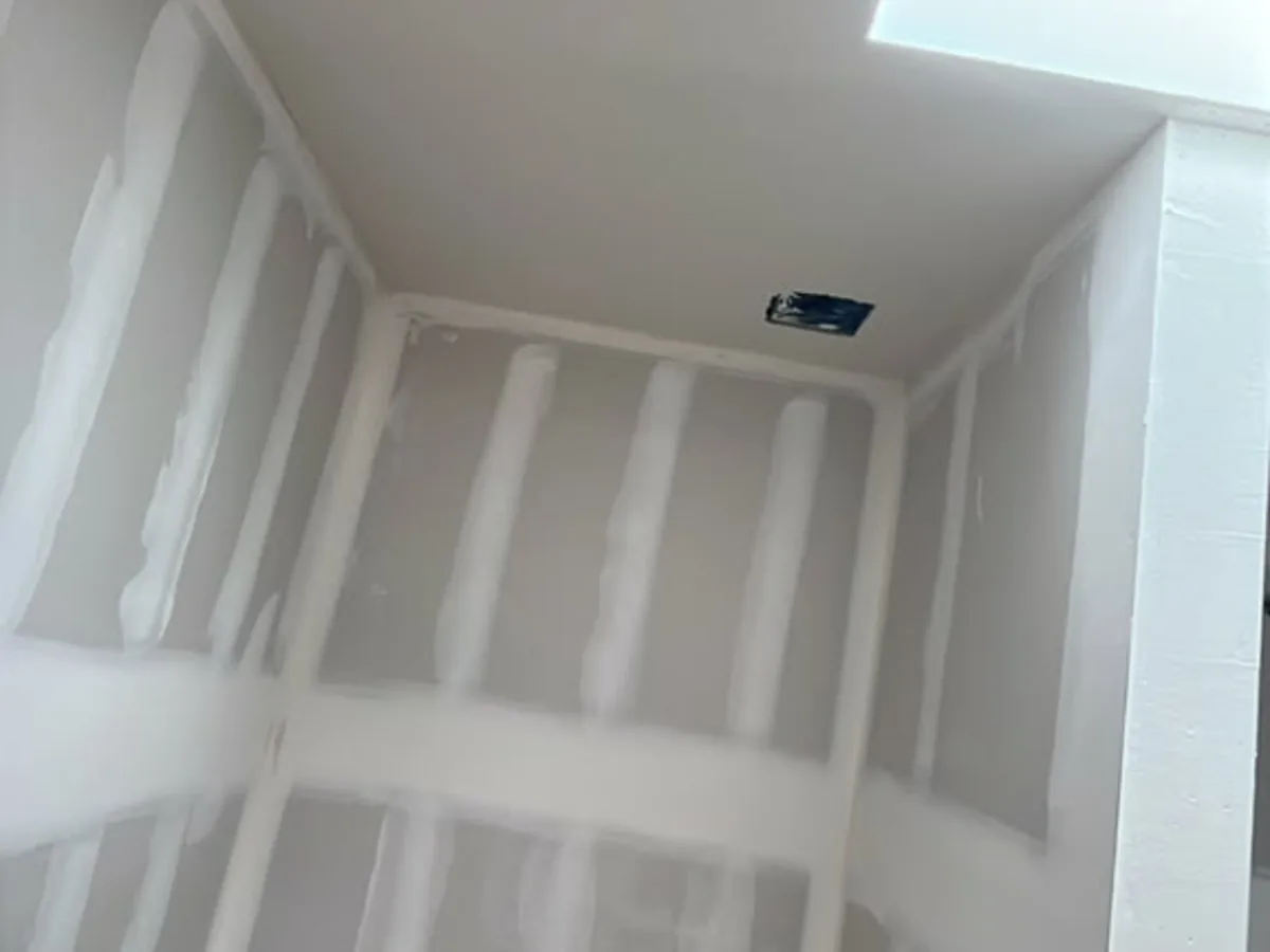 Drywall installation and taping in a room lit by a skylight