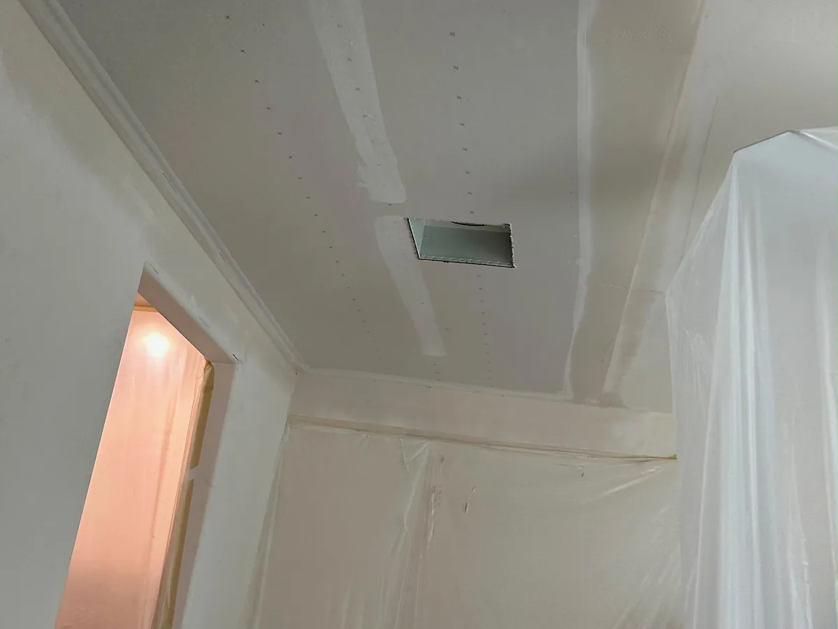 Ceiling repaired and taped around an air vent next to a doorway